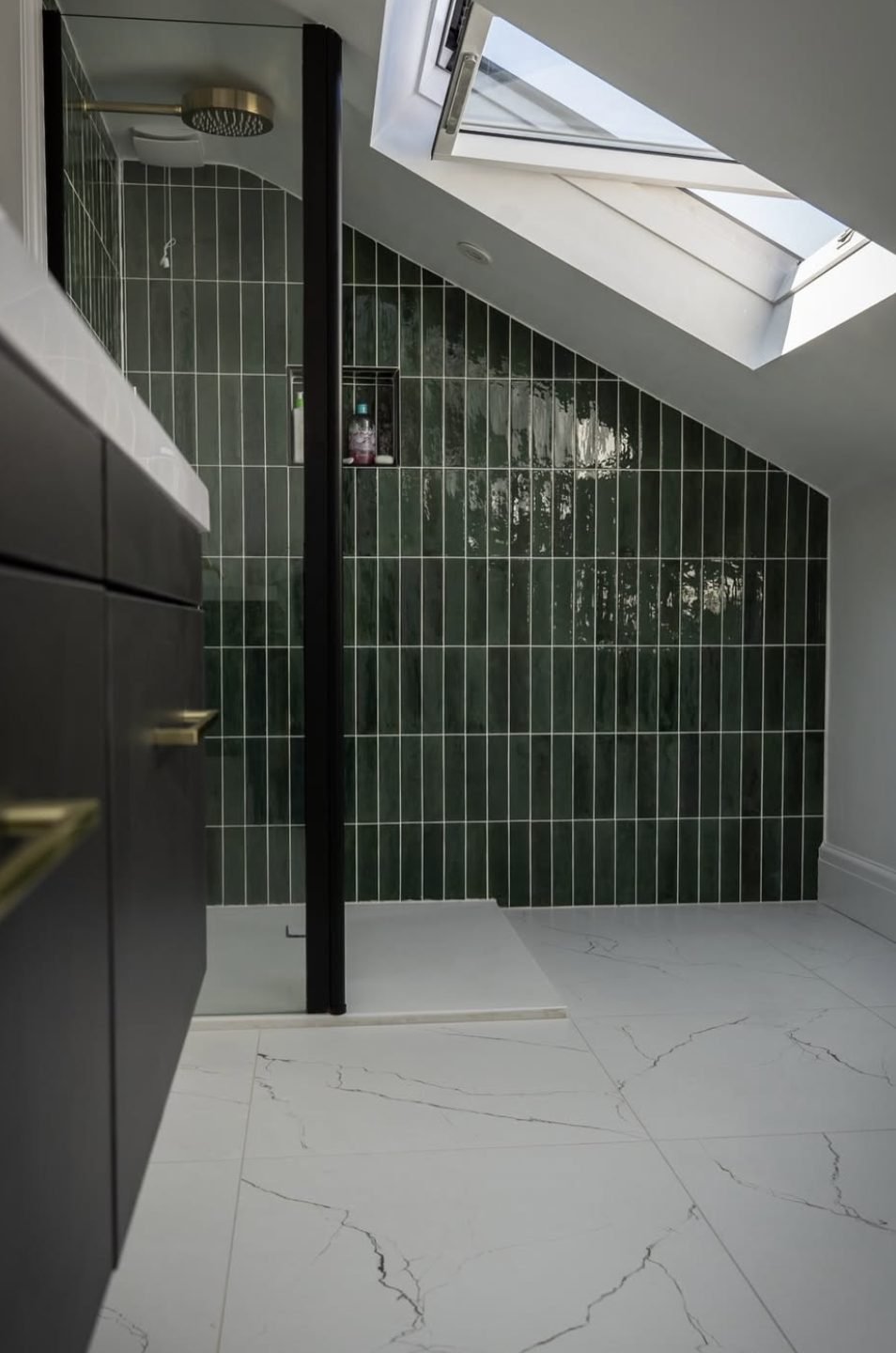 Loft shower room with green vertical tiles, brass rainfall shower and rooflight