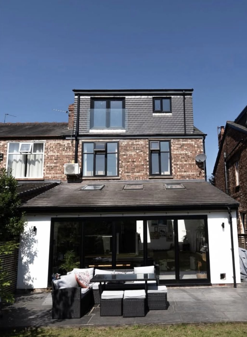 Rear dormer loft conversion with tile-hung cheeks and a glass Juliet balcony above brick walls and a rear extension